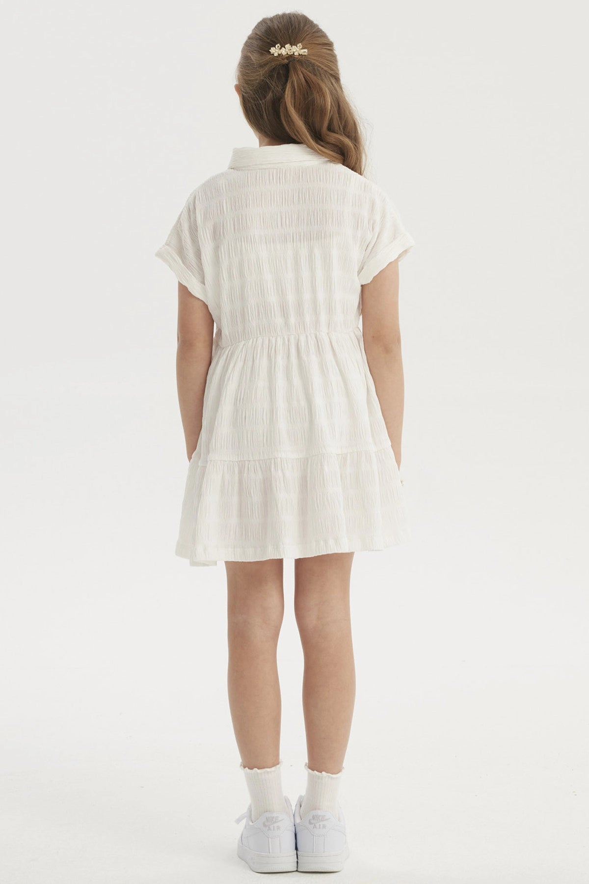 Vestido niña crudo con cuello redondo y mangas cortas detalle de lazo en cintura y diseño plisado liso