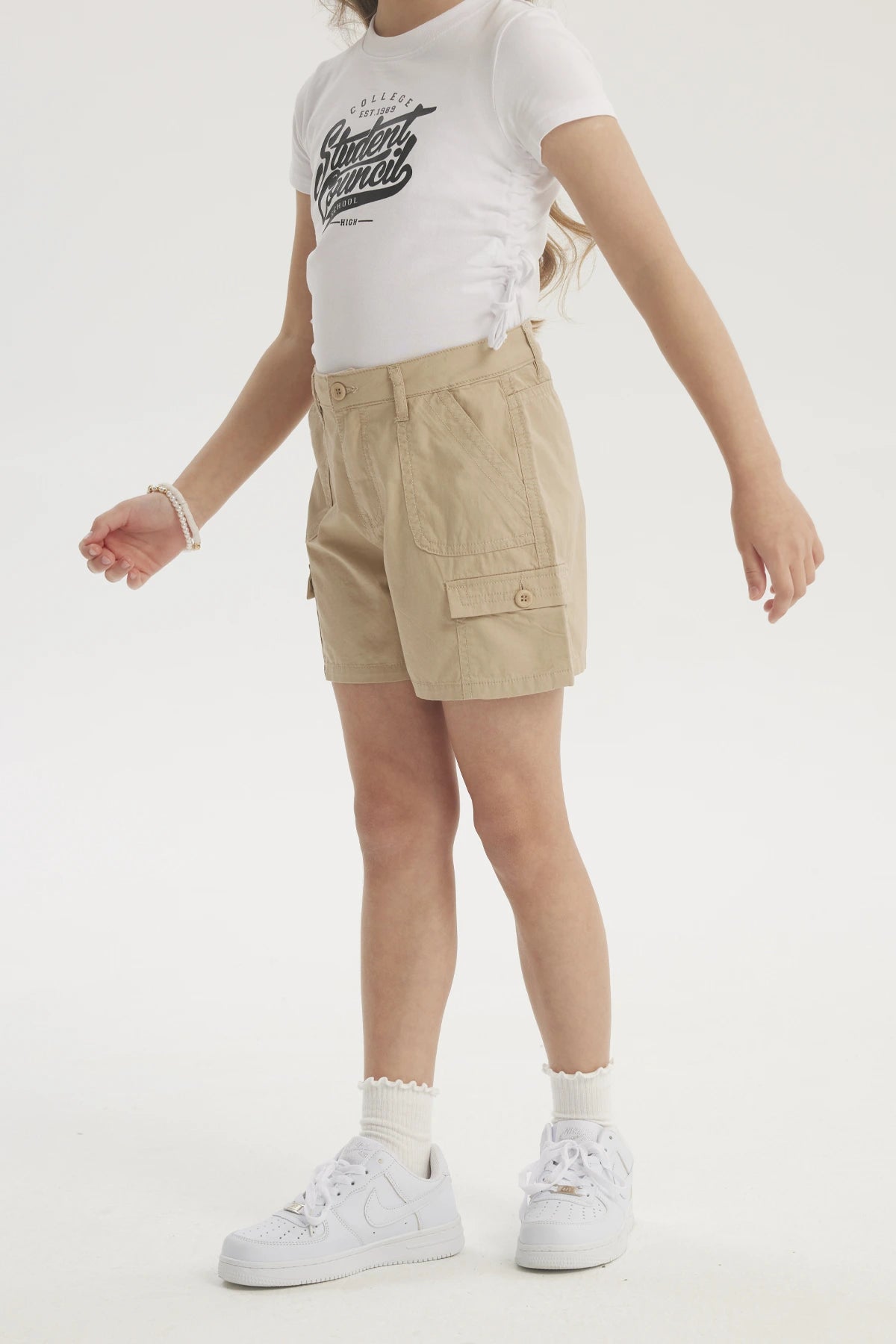 Short beige de gabardina para niña con bolsillos cargo amplios y botón frontal diseño liso