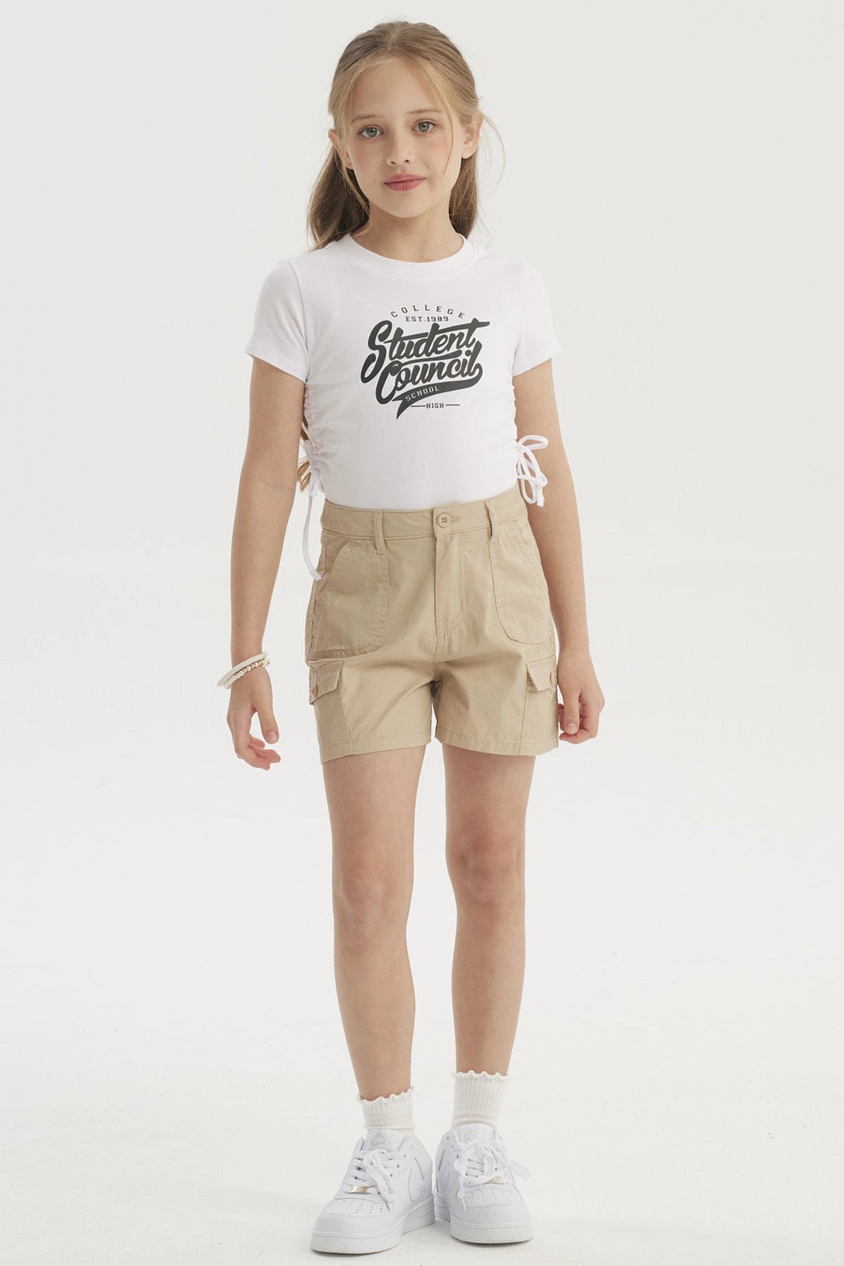 Short beige de gabardina para niña con bolsillos cargo amplios y botón frontal diseño liso
