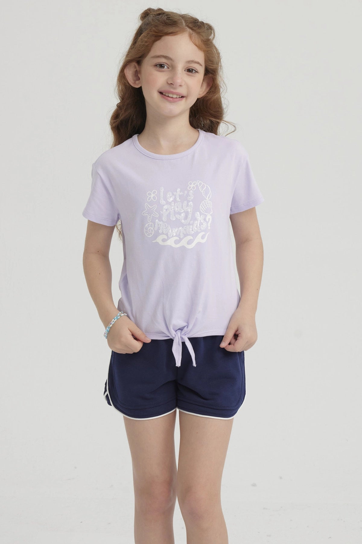 Polera morada para niña con nudo en el frente y estampa de conchas y olas en el pecho estilo dibujo infantil