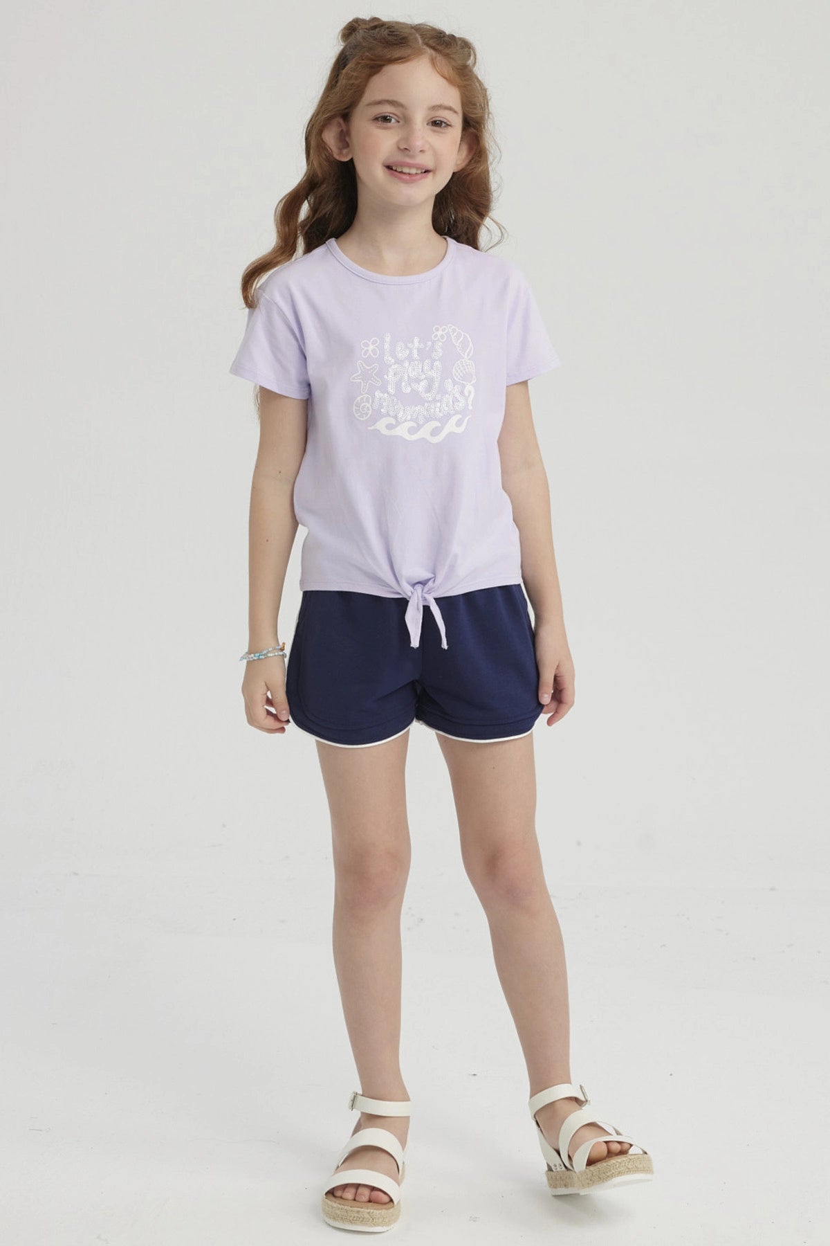 Polera morada para niña con nudo en el frente y estampa de conchas y olas en el pecho estilo dibujo infantil