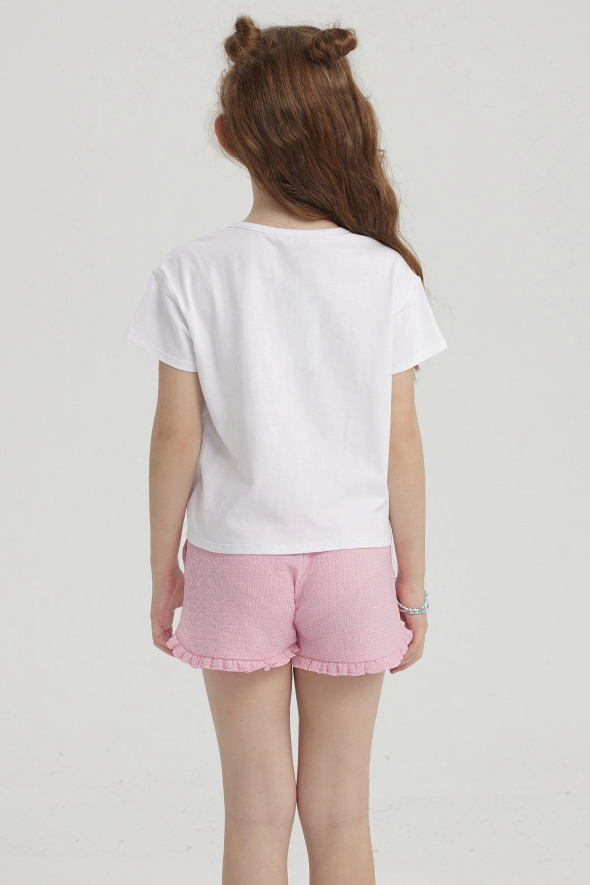 Polera blanca de niña con nudo frontal y estampado colorido que dice Sun Fun Girls con palmera pequeña al lado derecho