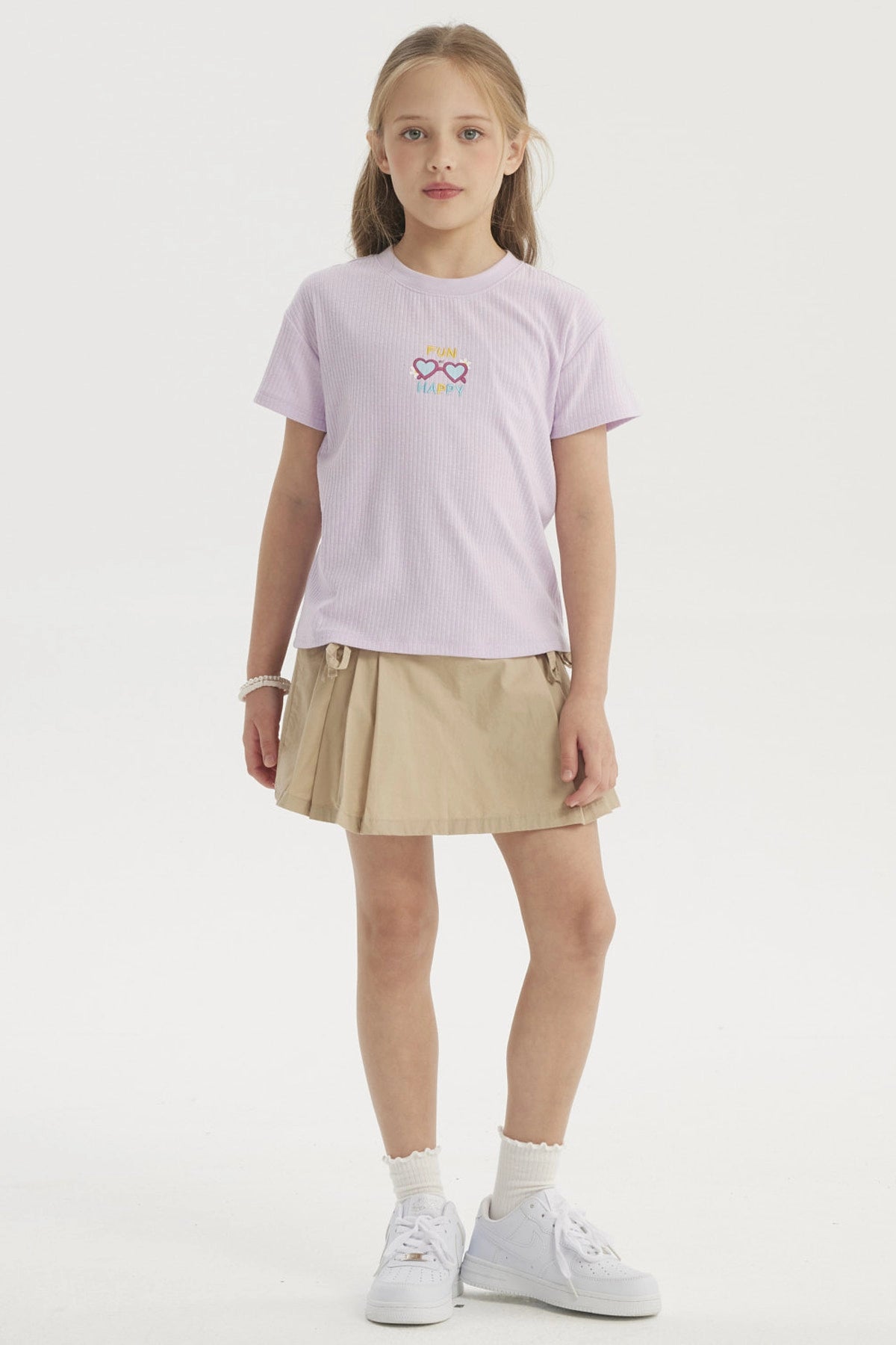 Polera lila de niña con diseño pequeño de gafas corazón y texto Fun Happy en el centro estilo gráfico colorido