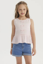 Polera niña rosada sin mangas con cintas decorativas en el frente y volantes en la cintura diseño liso