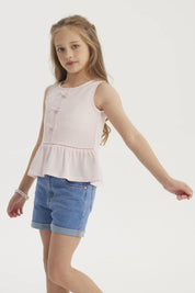 Polera niña rosada sin mangas con cintas decorativas en el frente y volantes en la cintura diseño liso