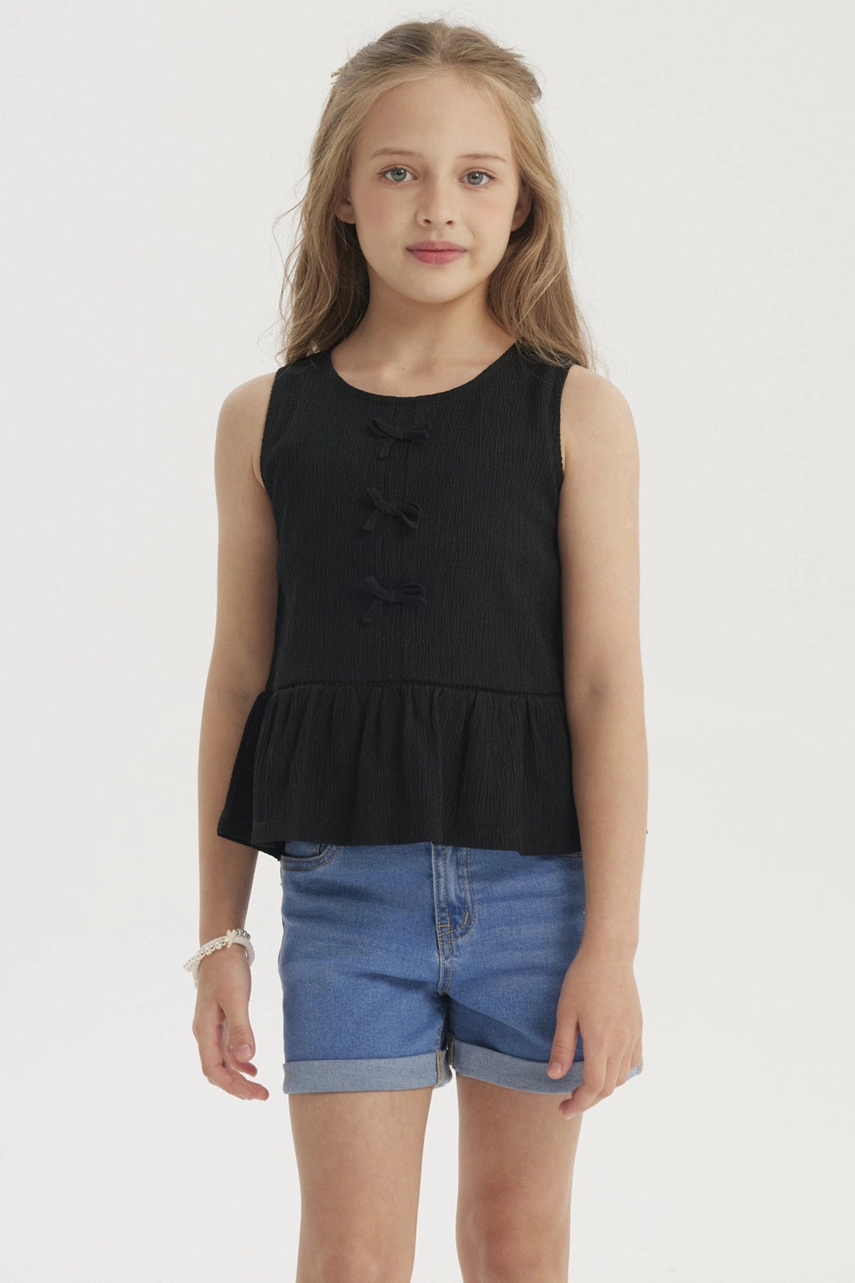 Polera negra sin mangas con cintas en el pecho y diseño de volante en la parte inferior prenda lisa