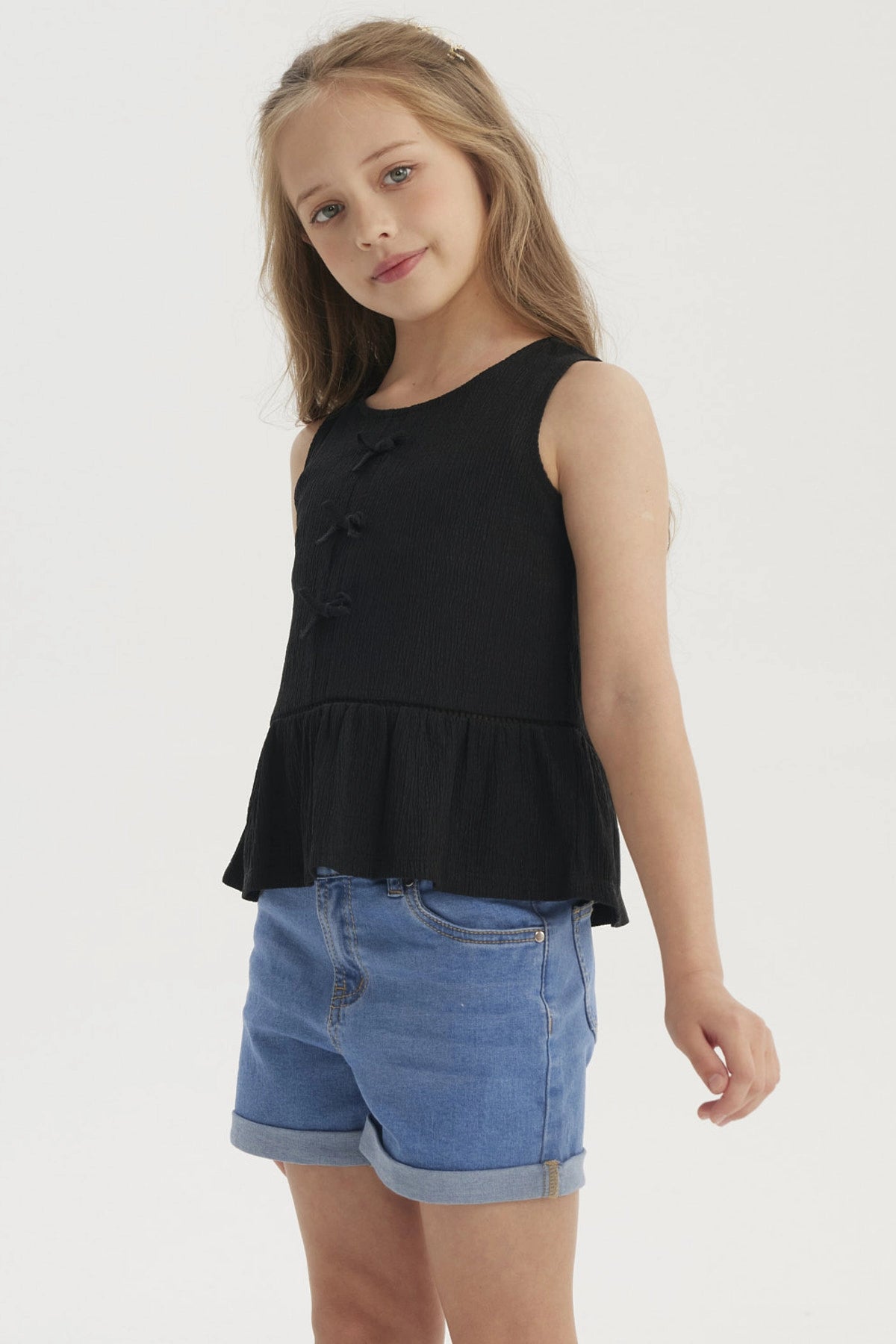 Polera negra sin mangas con cintas en el pecho y diseño de volante en la parte inferior prenda lisa