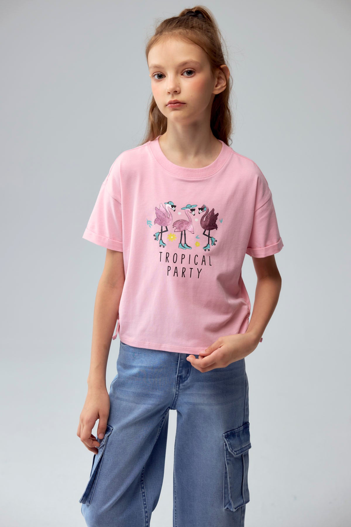 Polera rosada para niña con estampado de flamencos y texto Tropical Party