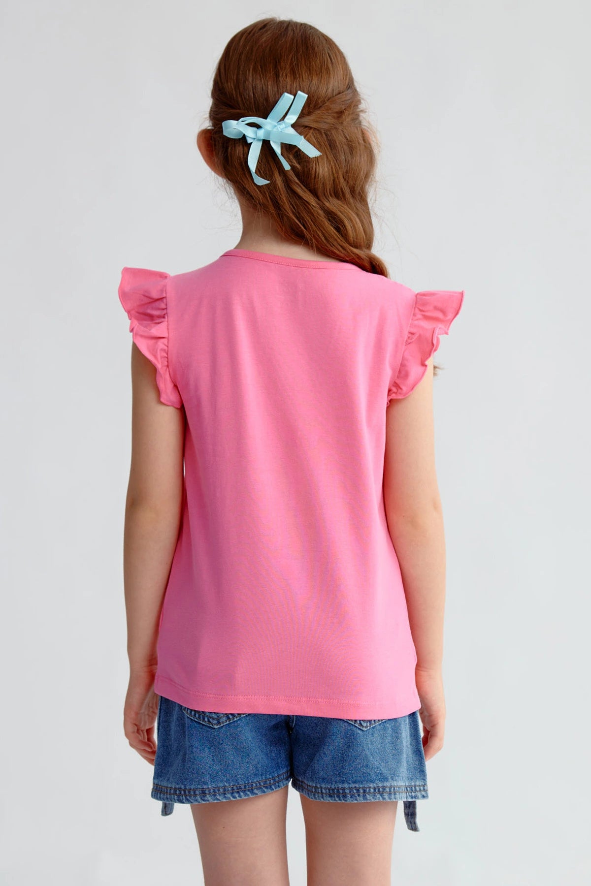 Polera niña fucsia con vuelos y diseño de conchas marinas en el frente