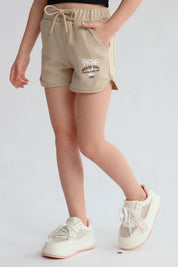 Short beige para niña con estampado de palmeras y texto en la pierna izquierda