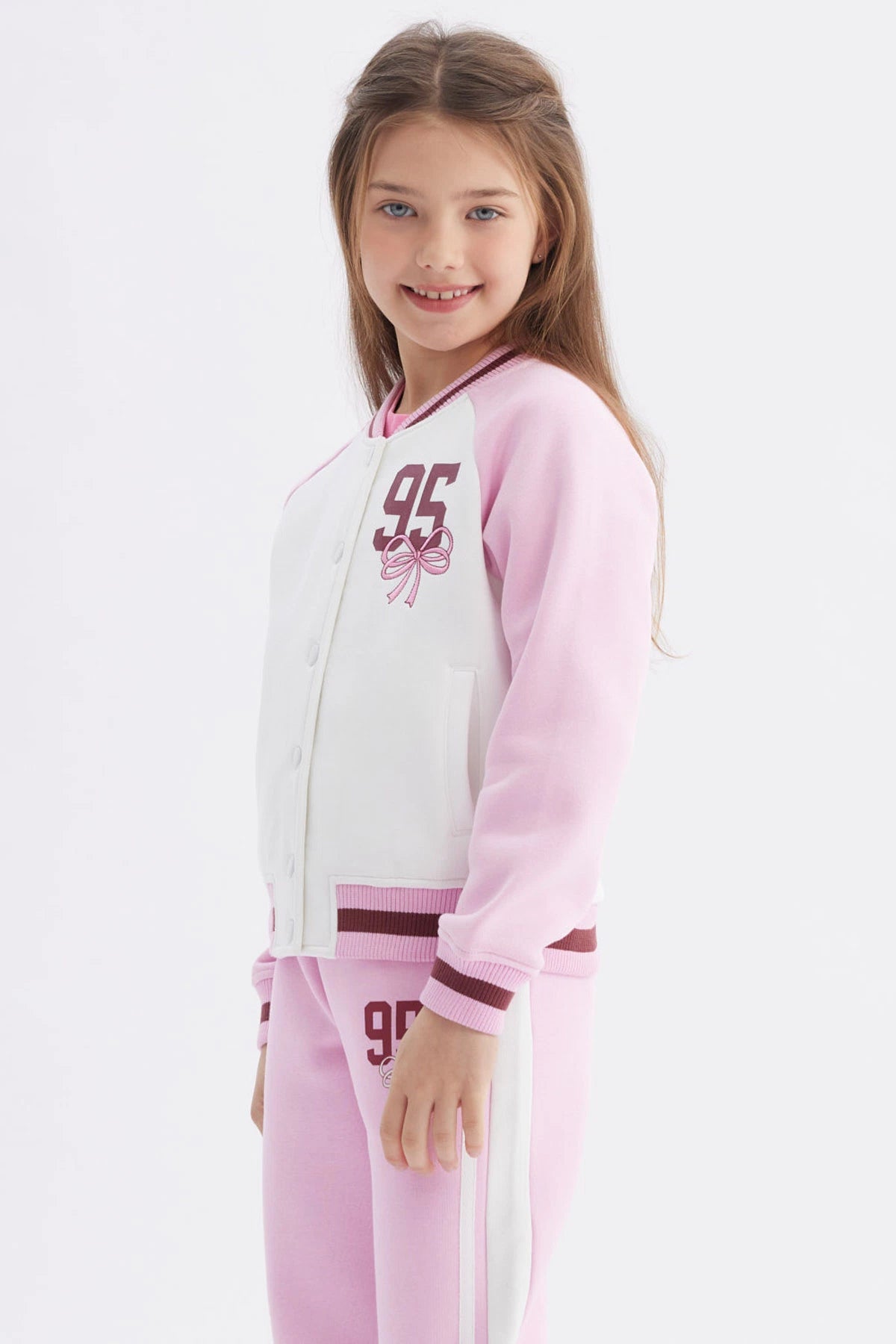 Chaqueta bomber rosado para niña con mangas raglán y estampado pequeño de número 95 y lazo en el pecho izquierdo