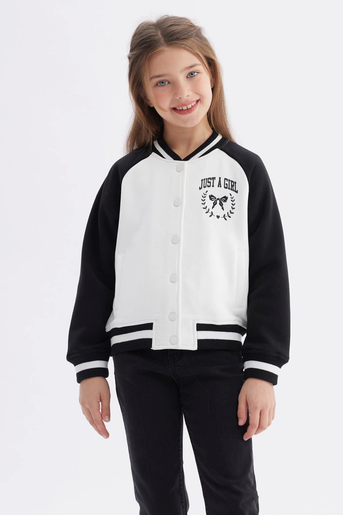 Chaqueta bomber negra para niña con mangas y cuello a rayas blancas estampa en el pecho de moño y texto Just a Girl