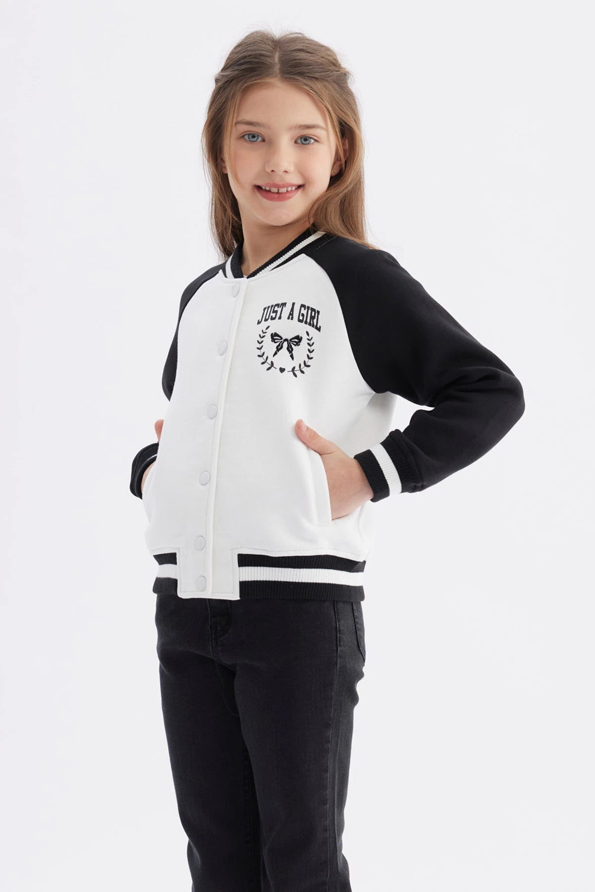 Chaqueta bomber negra para niña con mangas y cuello a rayas blancas estampa en el pecho de moño y texto Just a Girl