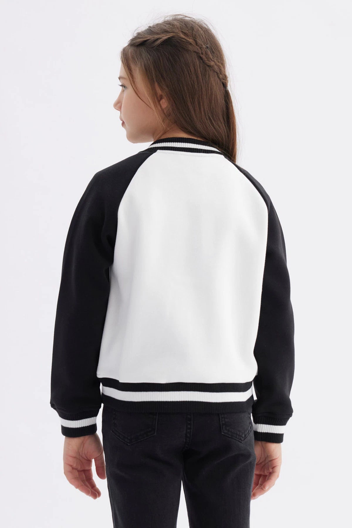 Chaqueta bomber negra para niña con mangas y cuello a rayas blancas estampa en el pecho de moño y texto Just a Girl