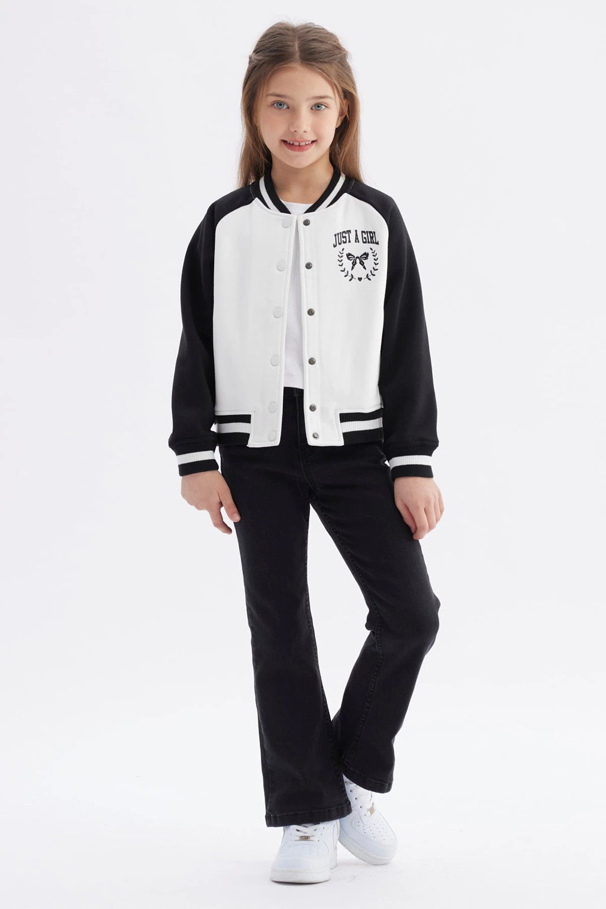 Chaqueta bomber negra para niña con mangas y cuello a rayas blancas estampa en el pecho de moño y texto Just a Girl
