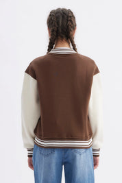 Chaqueta bomber café para niña con mangas crema y texto California en el pecho estilo universitario casual