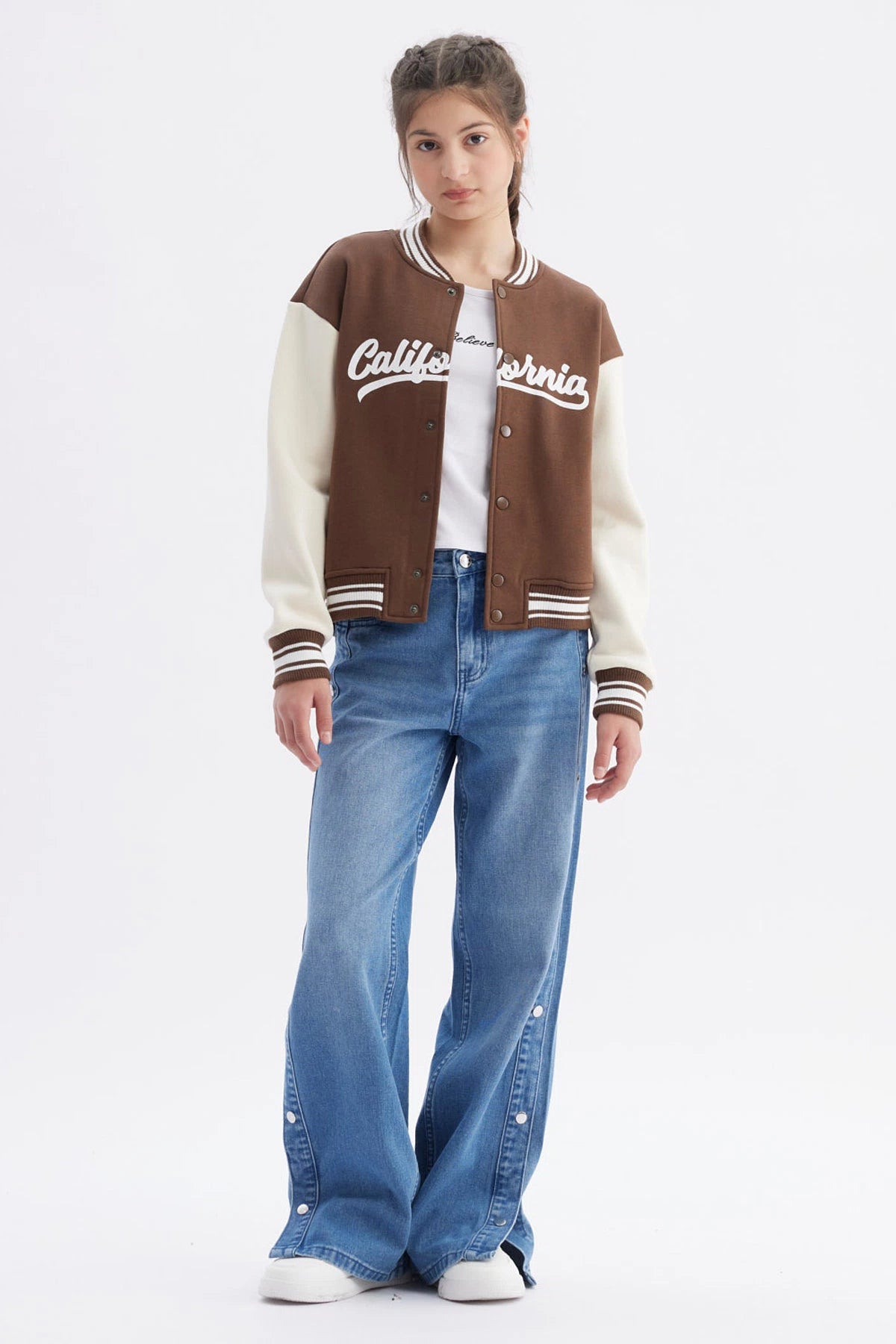 Chaqueta bomber café para niña con mangas crema y texto California en el pecho estilo universitario casual