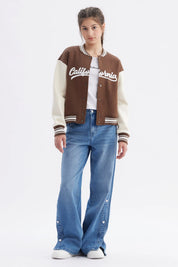 Chaqueta bomber café para niña con mangas crema y texto California en el pecho estilo universitario casual