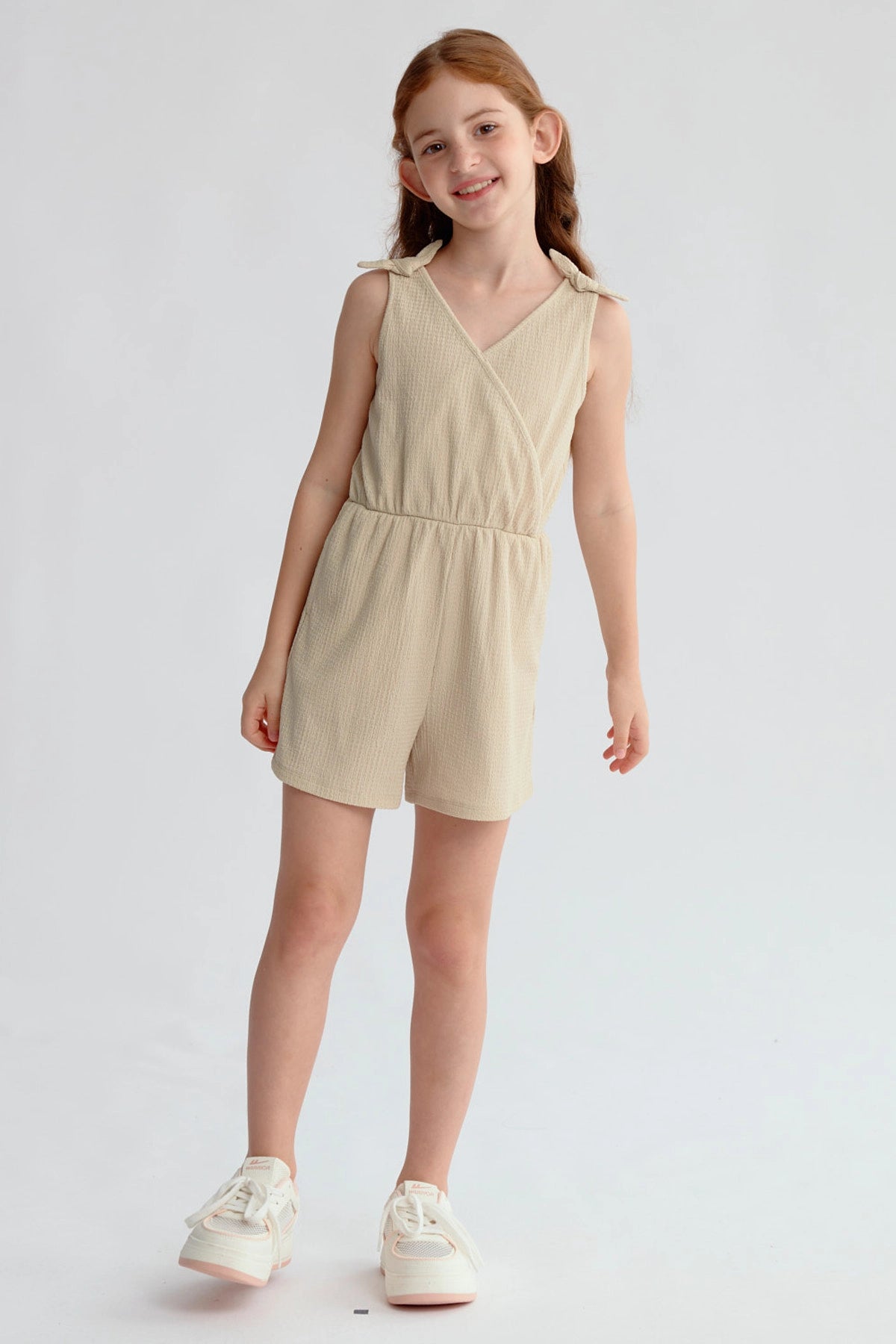 Enterito beige para niña con nudos en hombros y ajuste en la cintura