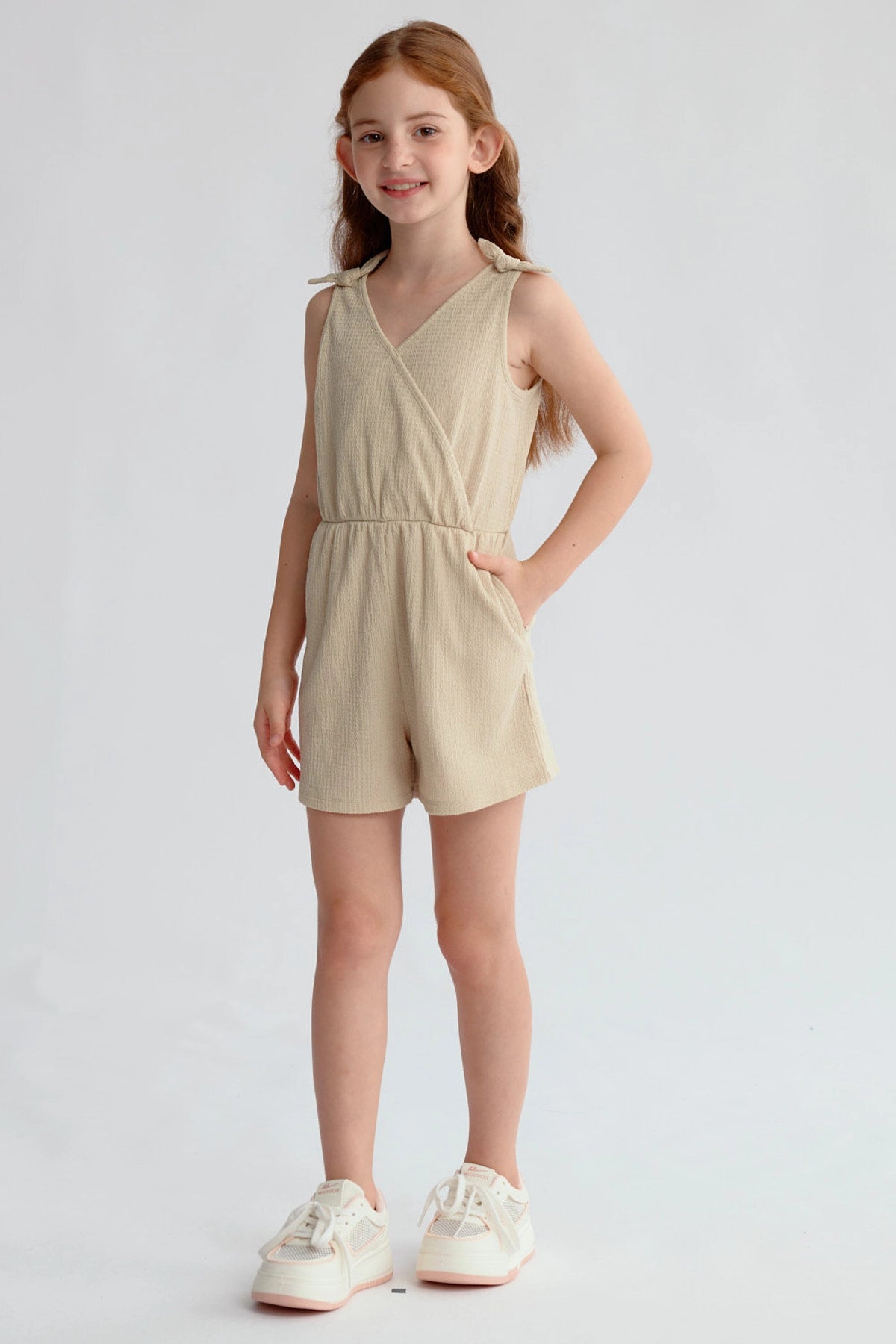 Enterito beige para niña con nudos en hombros y ajuste en la cintura