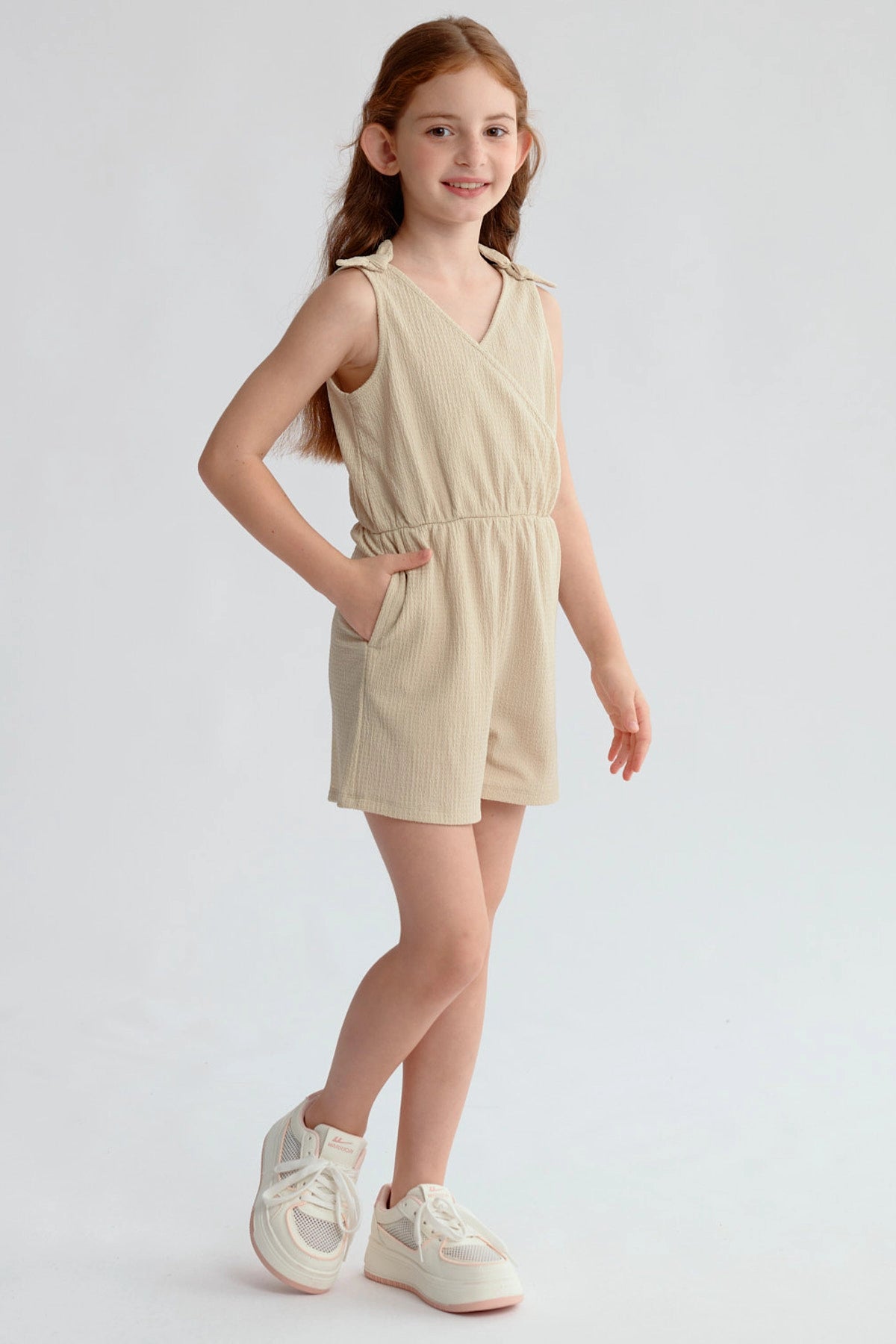 Enterito beige para niña con nudos en hombros y ajuste en la cintura