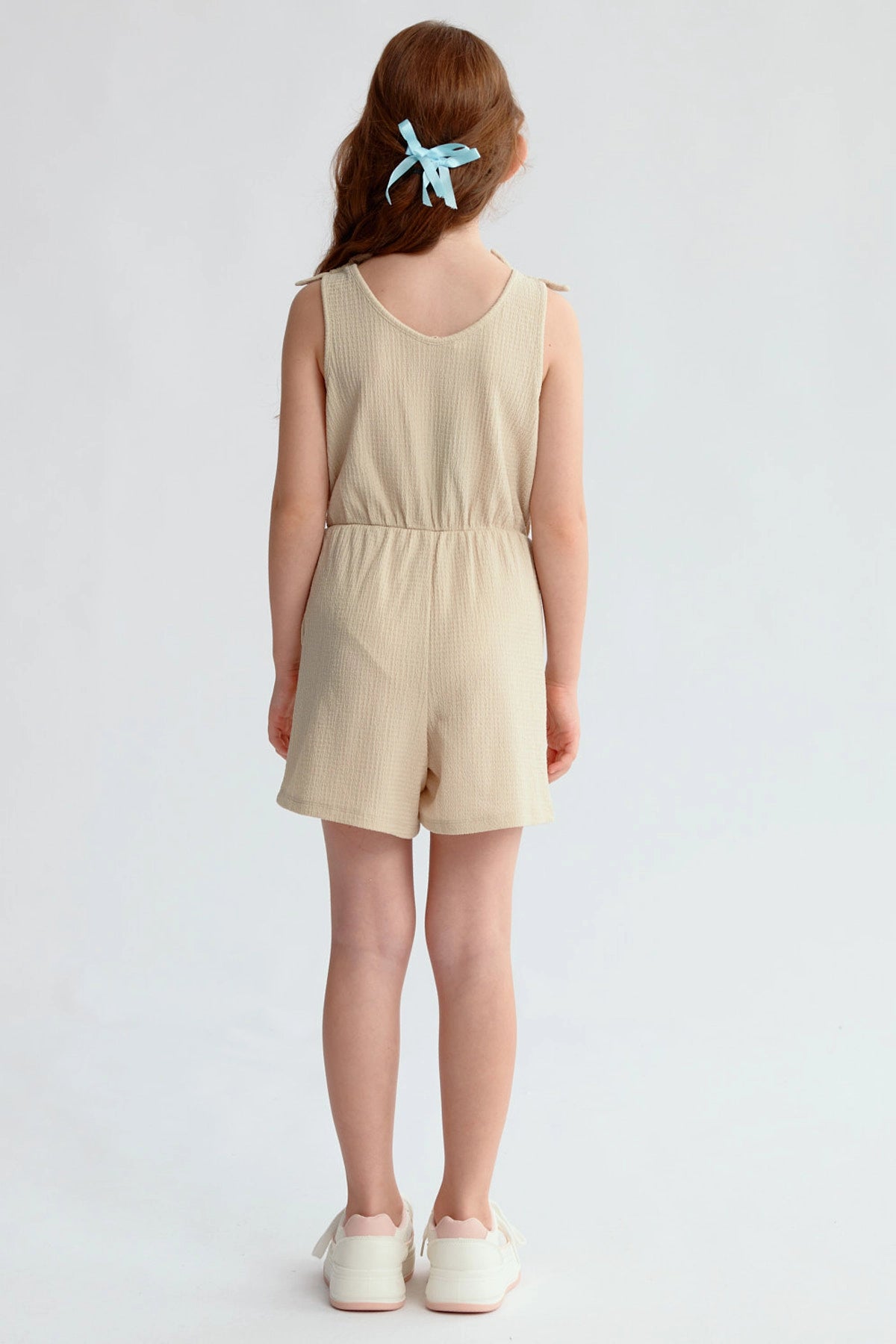 Enterito beige para niña con nudos en hombros y ajuste en la cintura