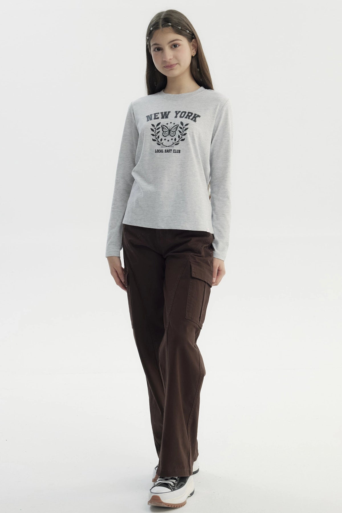 Polera niña gris melange con estampa central de mariposa y texto New York Local East Club en estilo universitario