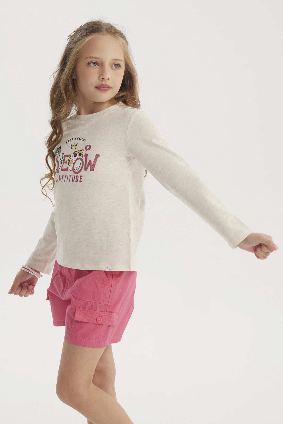 Polera beige para niña con estampado de gatos estilo caricatura al frente y texto Meow Cattitude en letras grandes