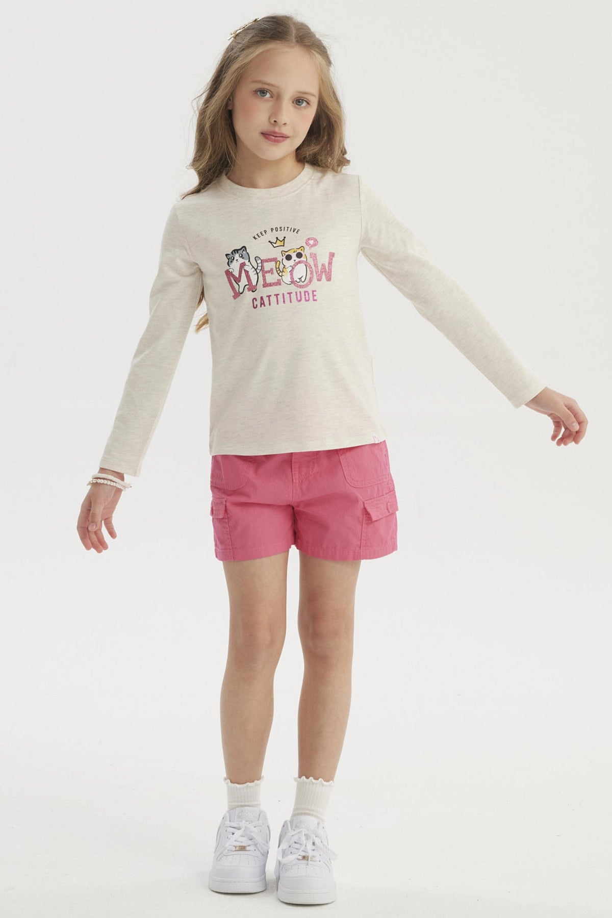 Polera beige para niña con estampado de gatos estilo caricatura al frente y texto Meow Cattitude en letras grandes