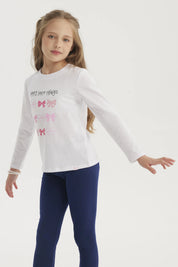 Polera blanca de niña con estampado de lazos en colores rosados y rojos en el centro con texto Happy little things