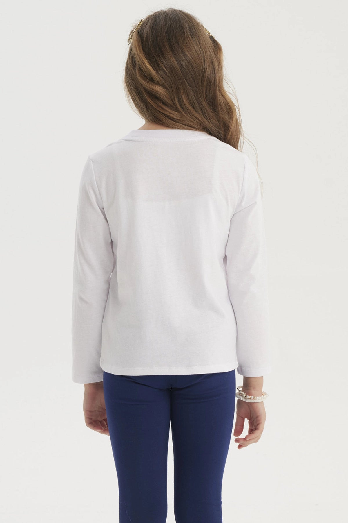 Polera blanca de niña con estampado de lazos en colores rosados y rojos en el centro con texto Happy little things