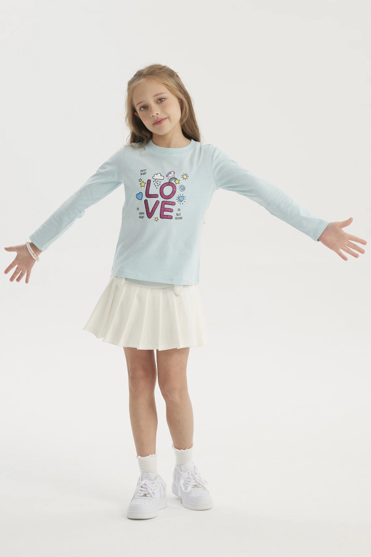Polera niña celeste con estampa LOVE en letras grandes y coloridas con estrellas y corazones pequeños en el centro