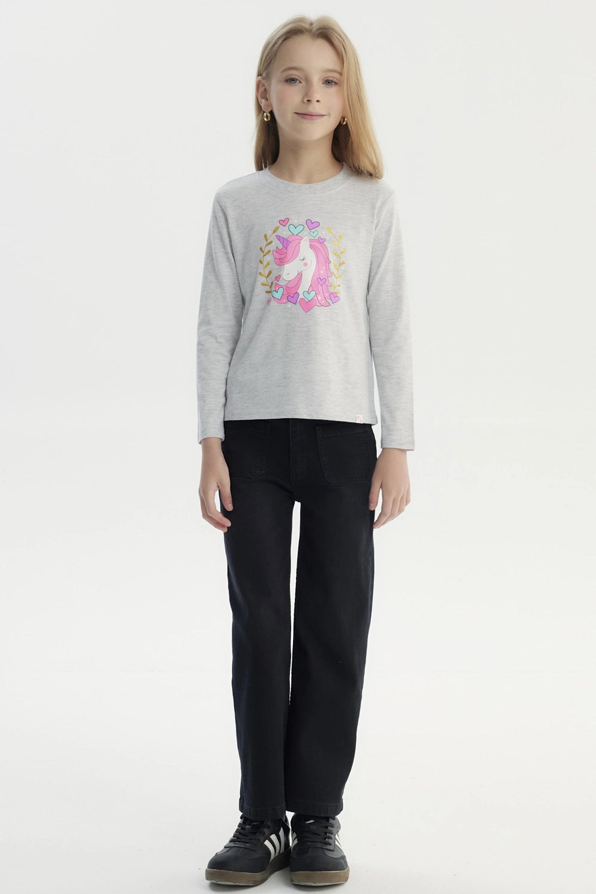 Polera gris melange de niña con estampa central de unicornio rosado rodeado de corazones y hojas doradas estilo dibujo