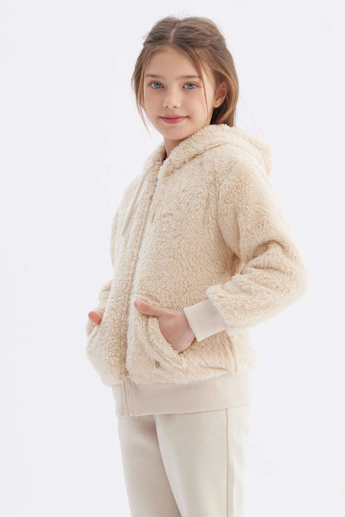 Polar niña beige con capucha y textura peluda cierre frontal y bolsillos delanteros diseño liso cómodo y abrigador