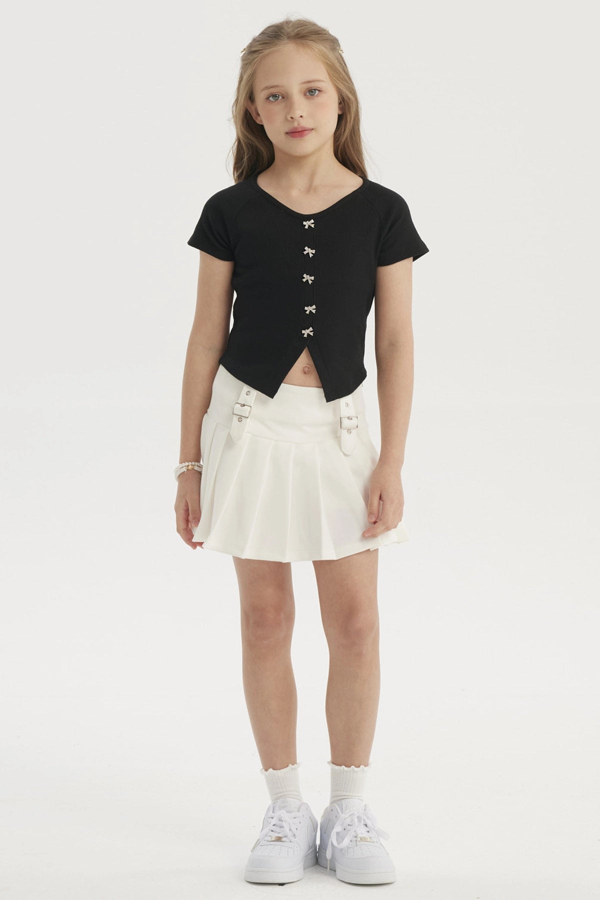 Polera negra para niña con botones de lazo pequeños en el frente estilo casual elegante sin estampa lisa