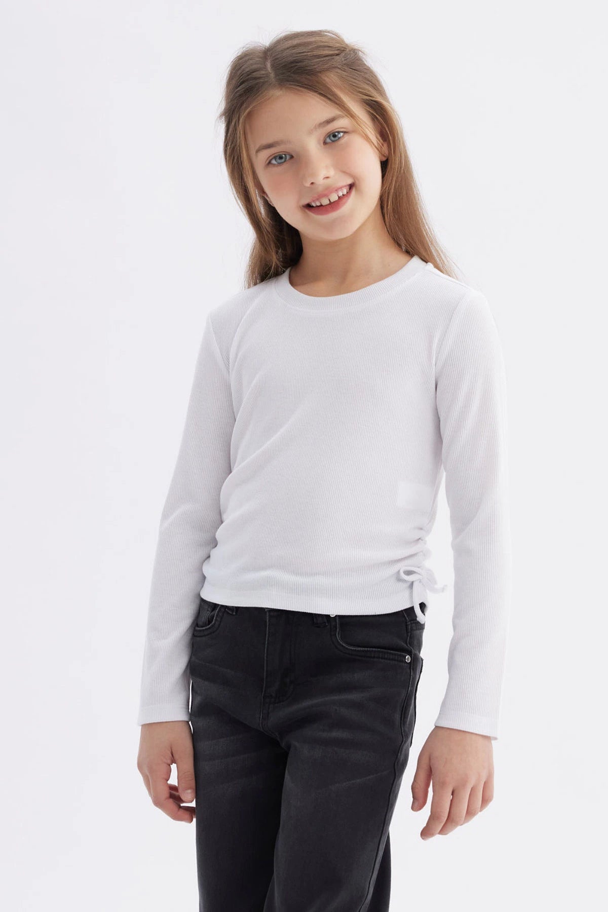 Polera blanca de manga larga para niña con diseño recogido en los laterales sin estampa lisa y minimalista