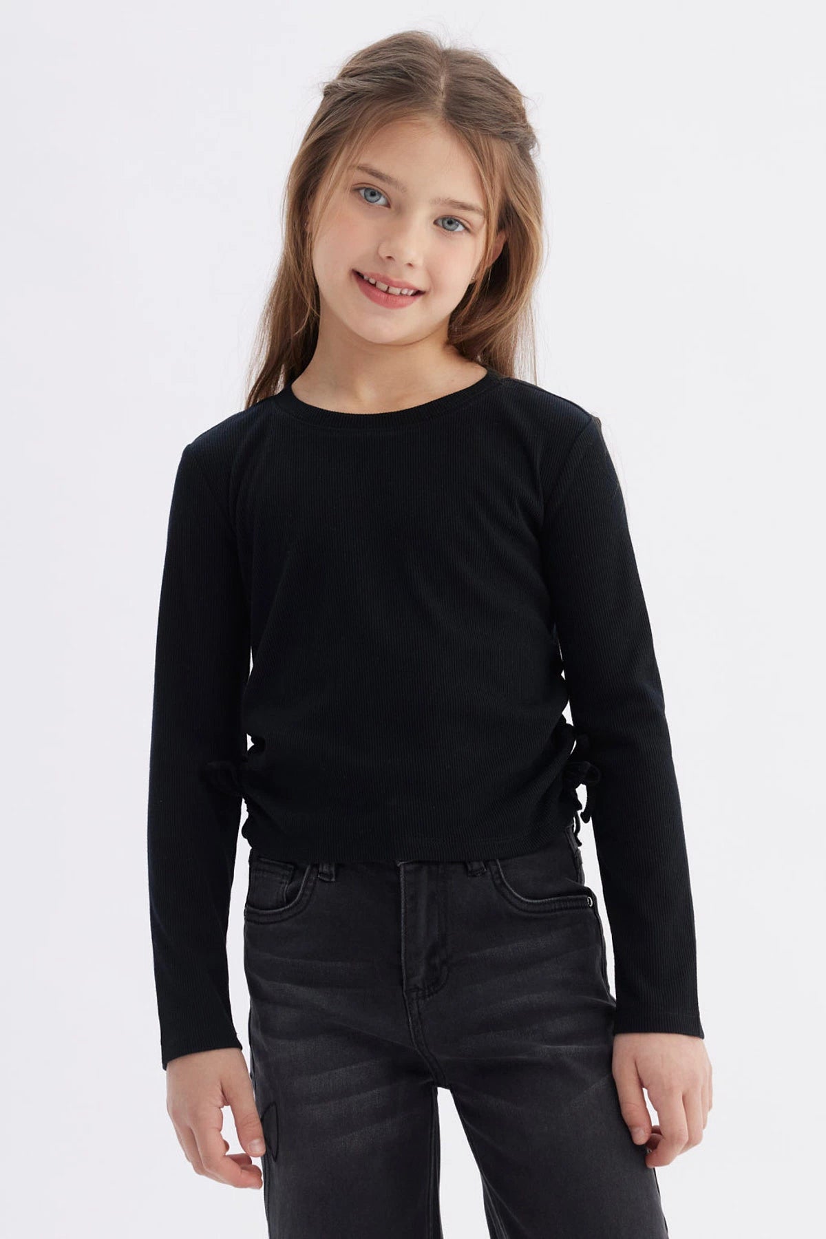 Polera negra para niña con diseño recogido en los laterales lisa y de manga larga ideal para un look casual