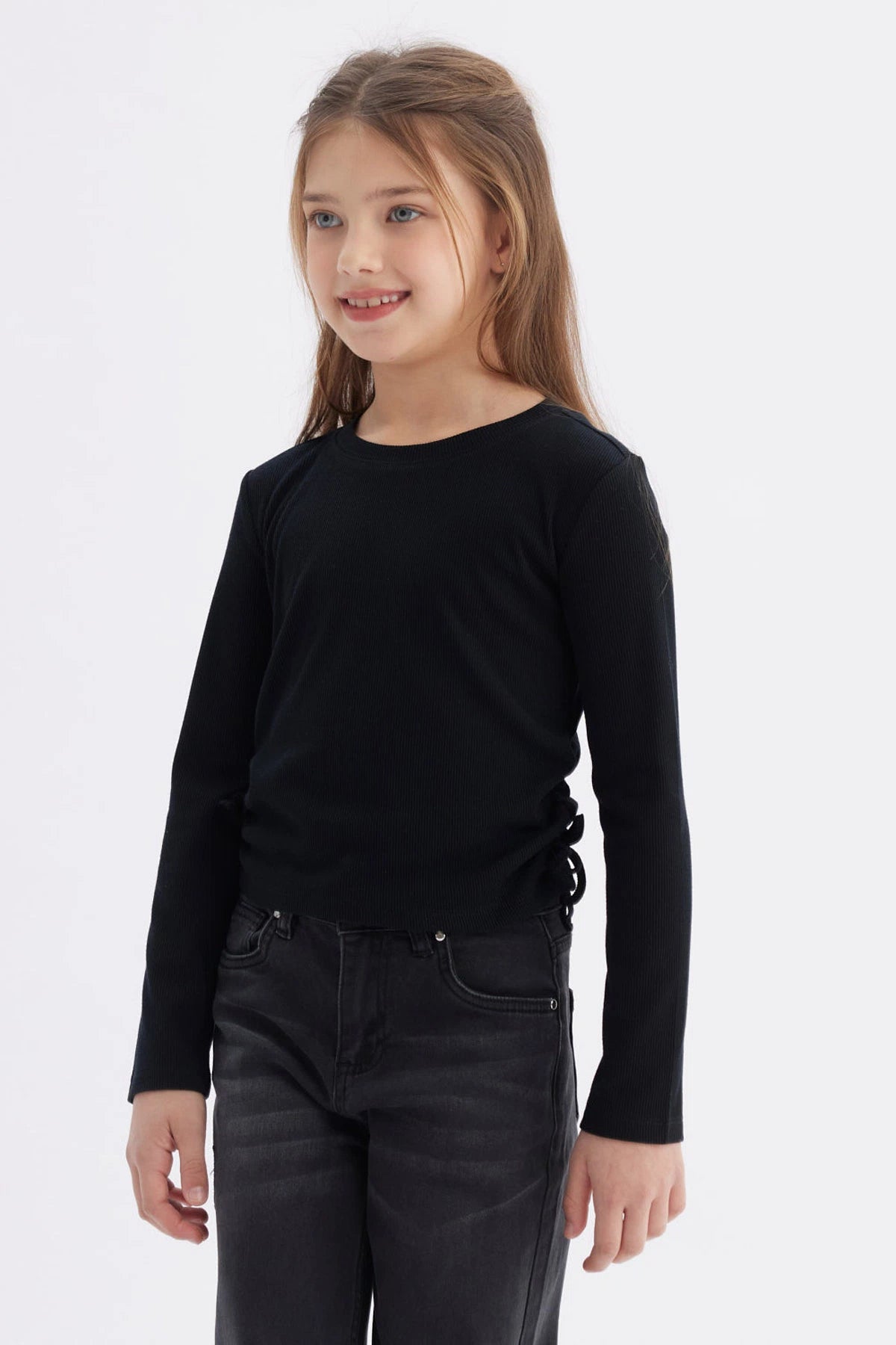 Polera negra para niña con diseño recogido en los laterales lisa y de manga larga ideal para un look casual