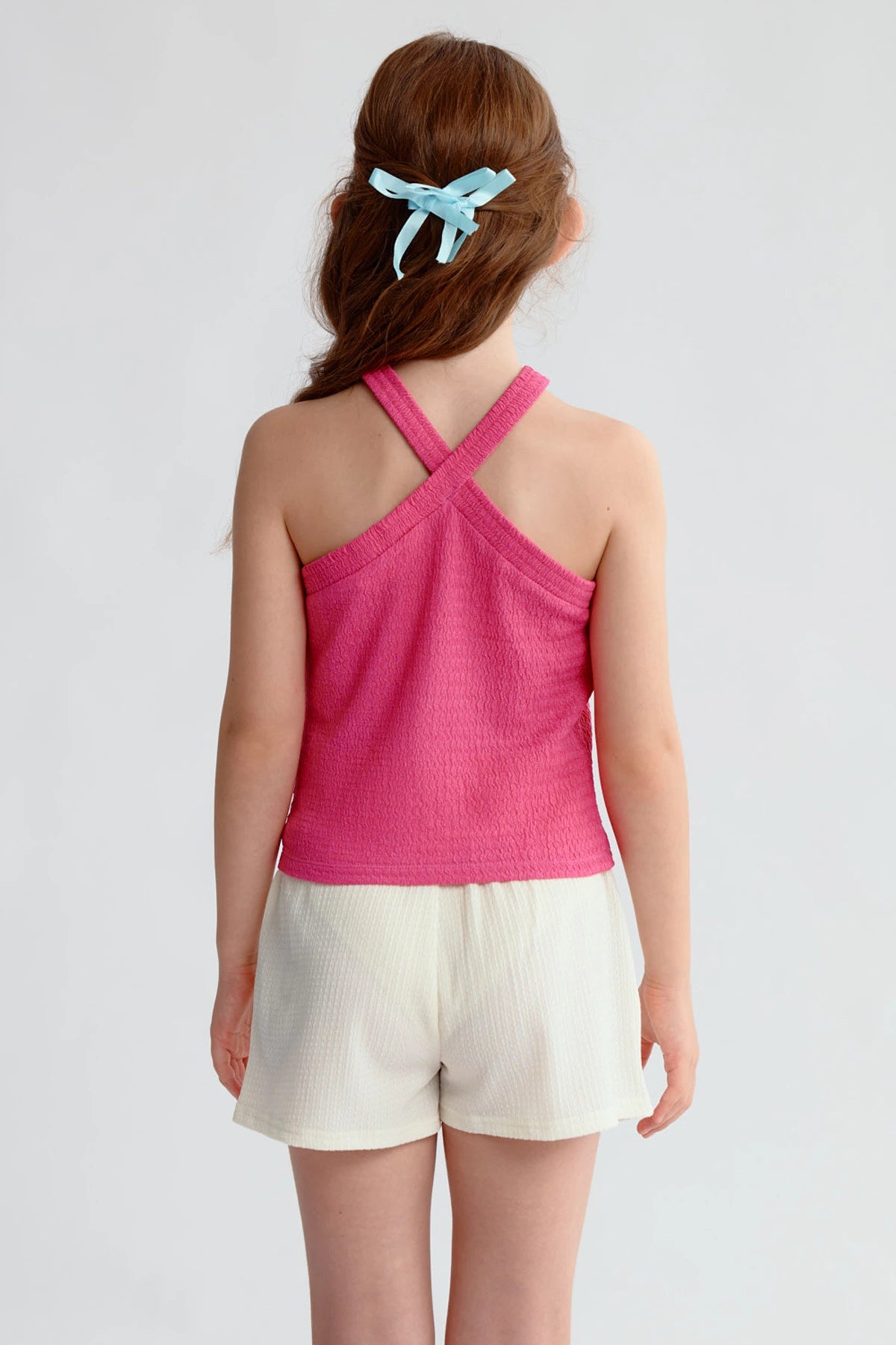 Peto niña color fucsia con textura y tirantes cruzados