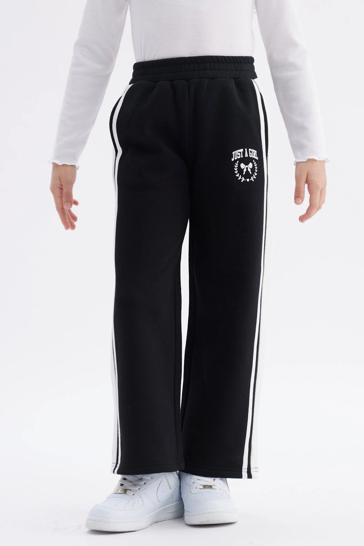 Pantalón buzo niña negro con pierna ancha y franjas blancas Just a Girl en el muslo diseño casual y cómodo