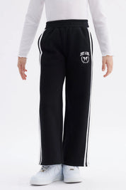 Pantalón buzo niña negro con pierna ancha y franjas blancas Just a Girl en el muslo diseño casual y cómodo