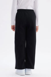 Pantalón buzo niña negro con pierna ancha y franjas blancas Just a Girl en el muslo diseño casual y cómodo