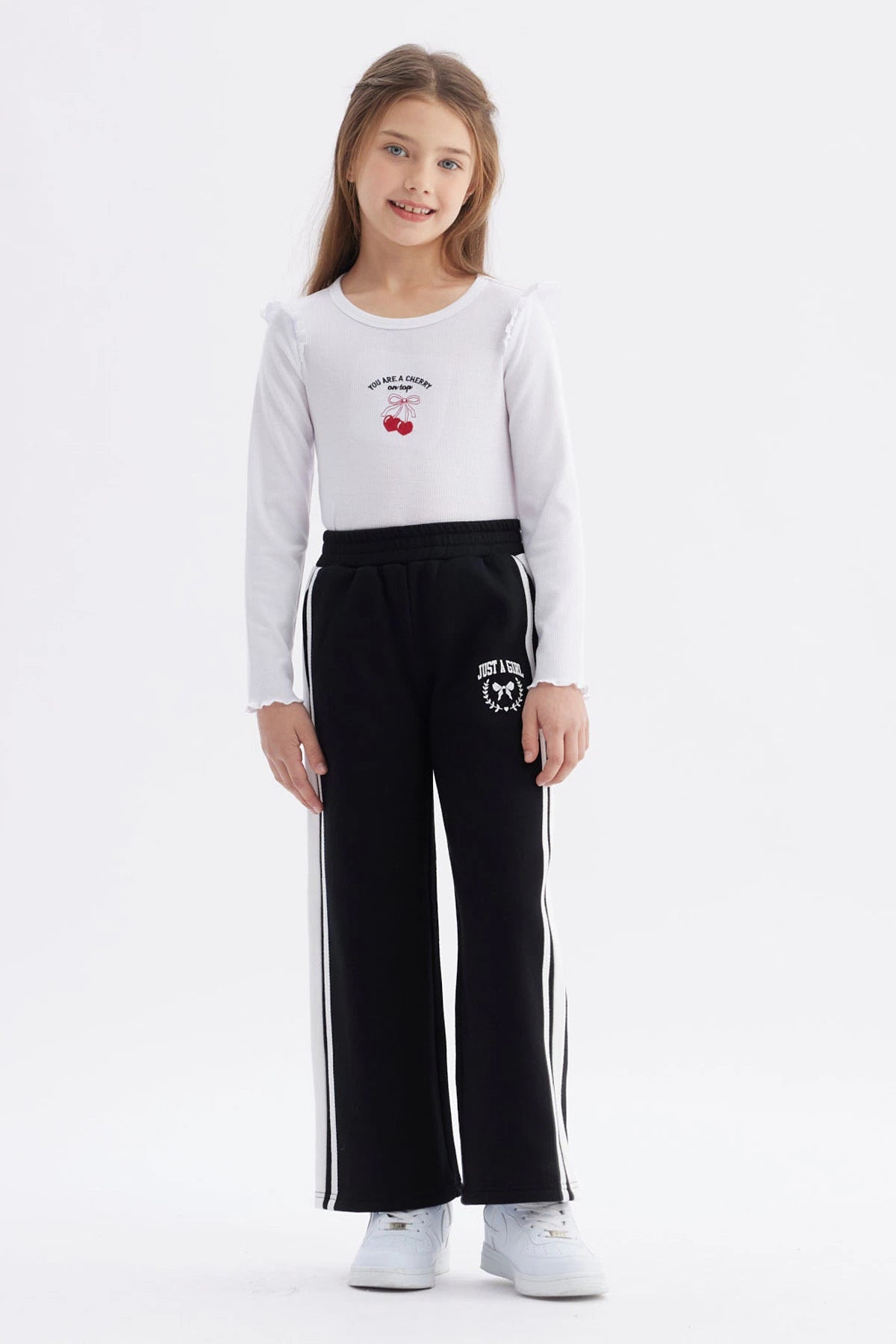 Pantalón buzo niña negro con pierna ancha y franjas blancas Just a Girl en el muslo diseño casual y cómodo