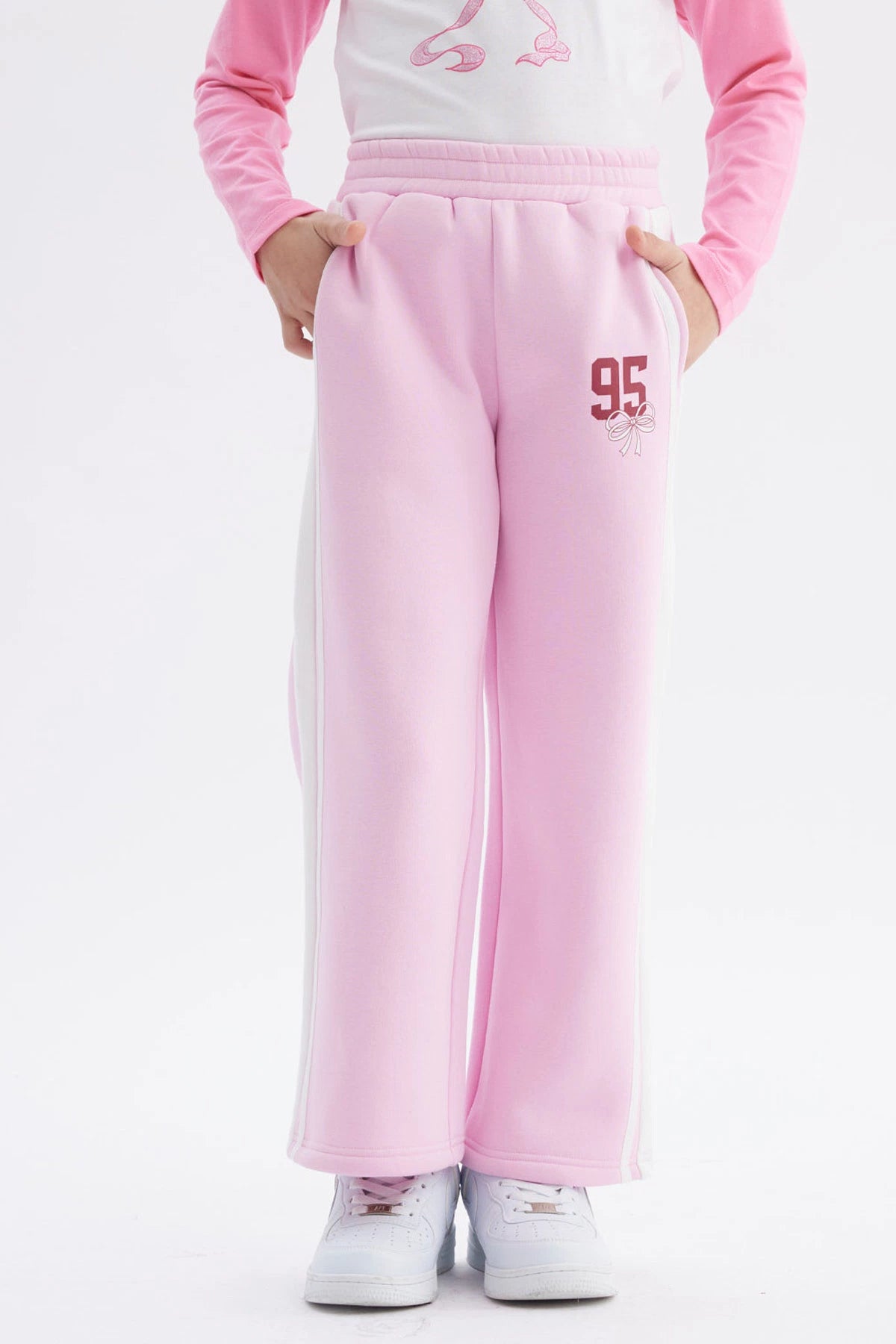 Pantalón buzo niña wide leg rosado con número 95 y lazo pequeño en la parte superior derecha estilo casual relajado