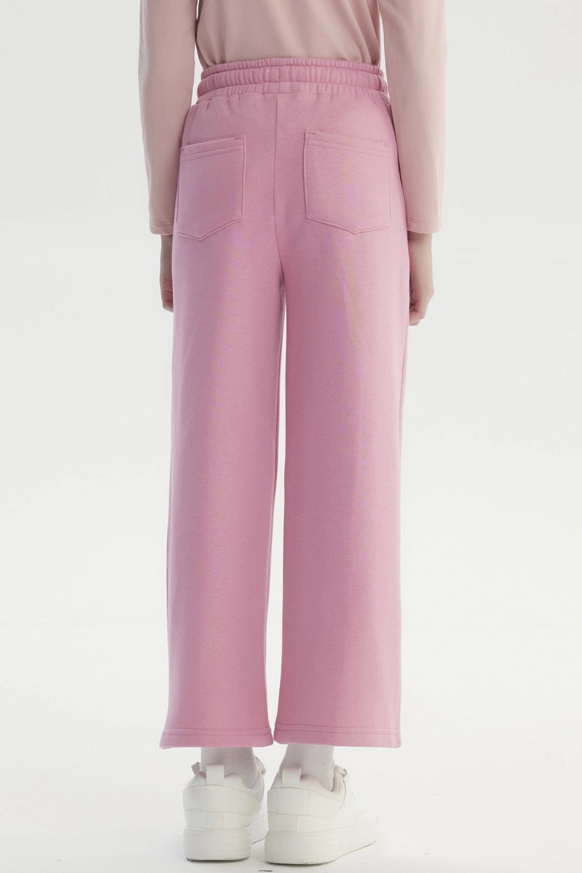 Pantalón buzo niña rosado de pierna ancha con cintura elástica y cordón ajustable diseño liso sin estampado