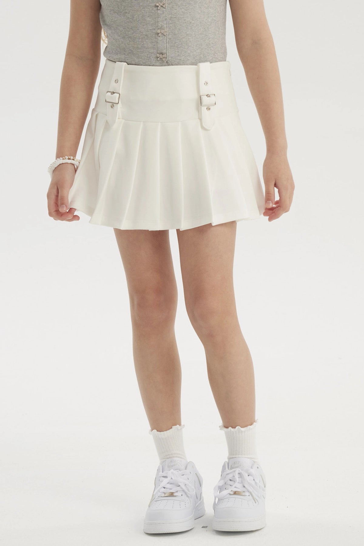 Falda niña tableada blanca con hebillas en la cintura prenda lisa ideal para un look fresco y cómodo