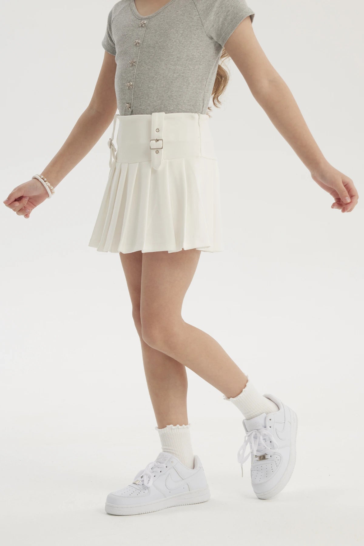Falda niña tableada blanca con hebillas en la cintura prenda lisa ideal para un look fresco y cómodo