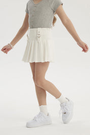 Falda niña tableada blanca con hebillas en la cintura prenda lisa ideal para un look fresco y cómodo