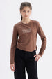 Polera niña slim café con diseño frontal de texto 'Elegant Ribbon' en estilo cursivo centrado sobre el pecho