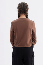 Polera niña slim café con diseño frontal de texto 'Elegant Ribbon' en estilo cursivo centrado sobre el pecho